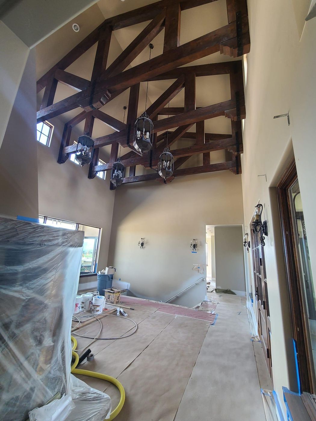 Great room with timber trusses mid-renovation, furniture wrapped in plastic