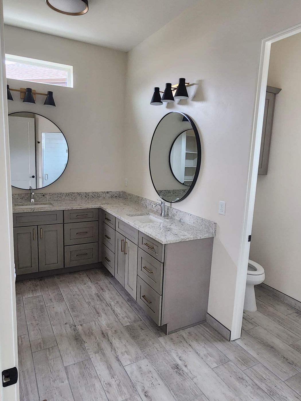Bathroom with round mirrors and a wood-look plank tile floor