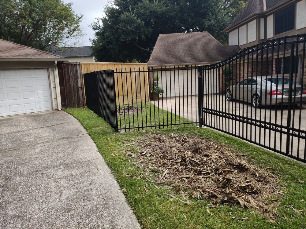 Black iron fence and drive gate along a curved driveway