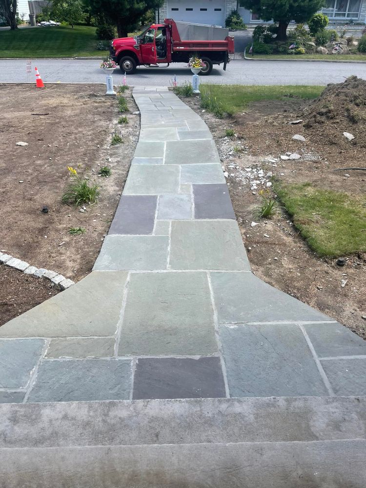 Bluestone walkway running from a driveway across a lawn toward the street