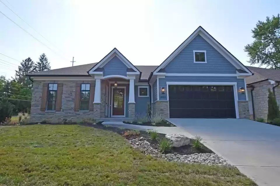 Blue-gray ranch home with stone, white trim and a dark garage door after exterior painting