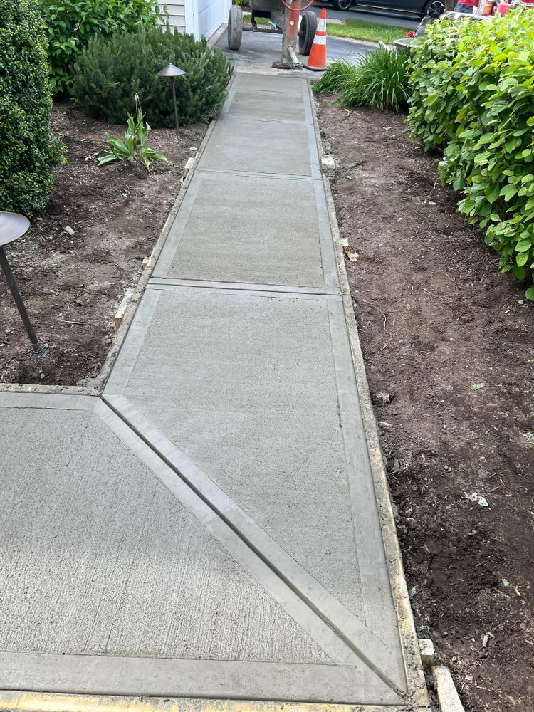 Freshly poured concrete walkway running through a lawn toward the street