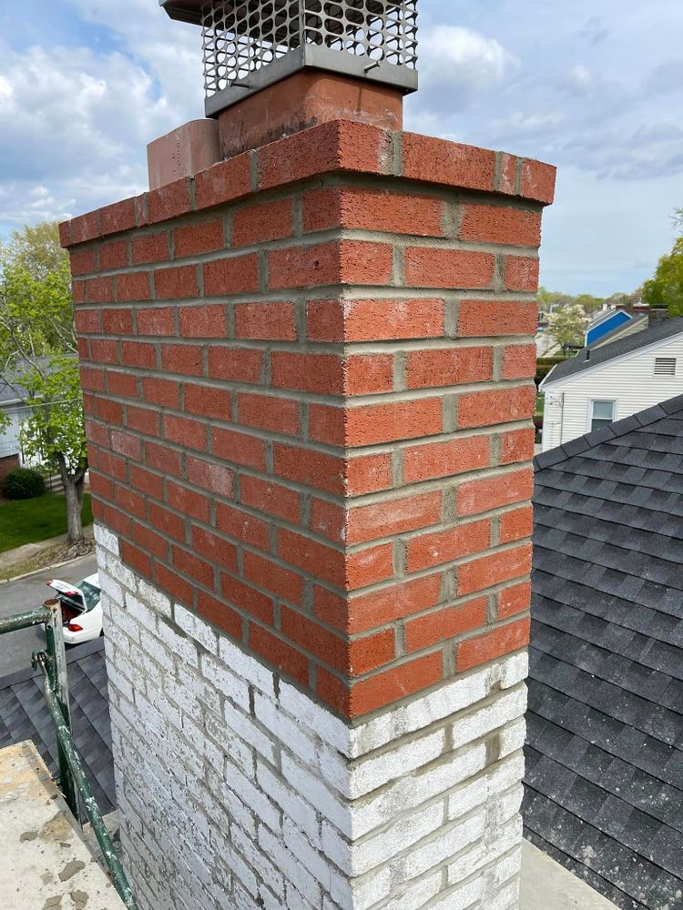 Rebuilt red brick chimney with a new crown rising above an asphalt shingle roof