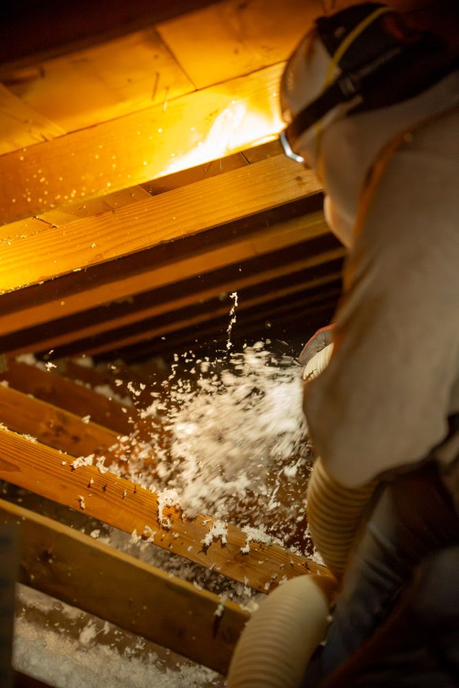 Foam Pro Insulation technician in a Phoenix attic wearing a headlamp, inspecting the insulation up close