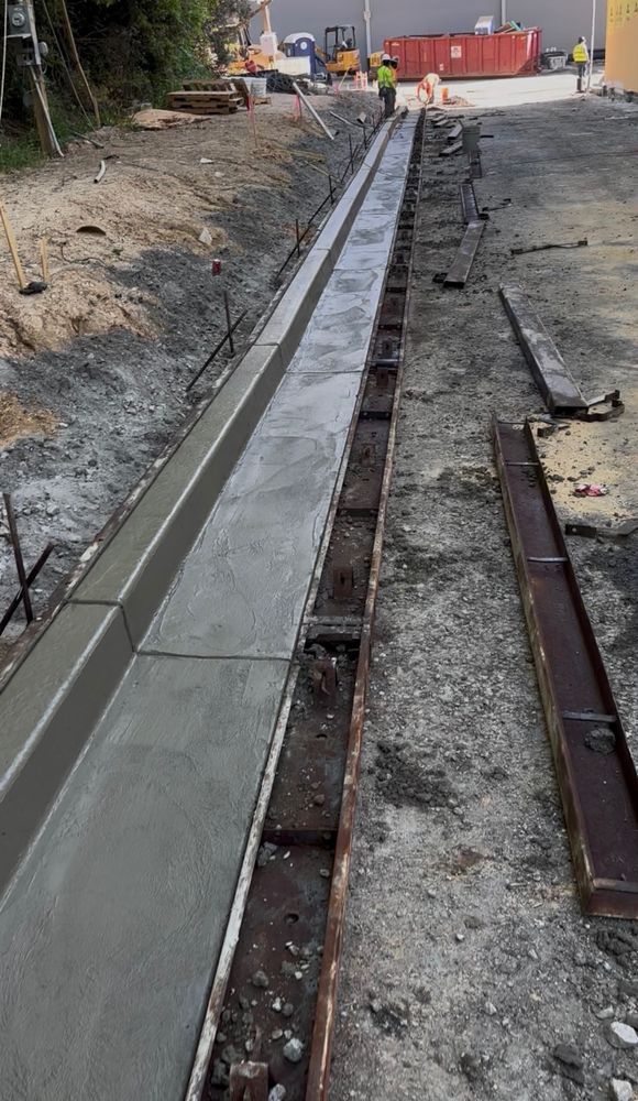 Finished concrete curb and gutter run alongside steel forms