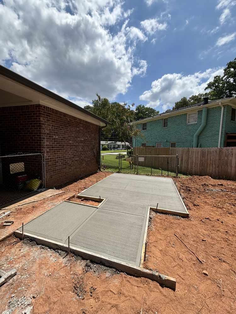 New residential concrete patio slab beside a brick home