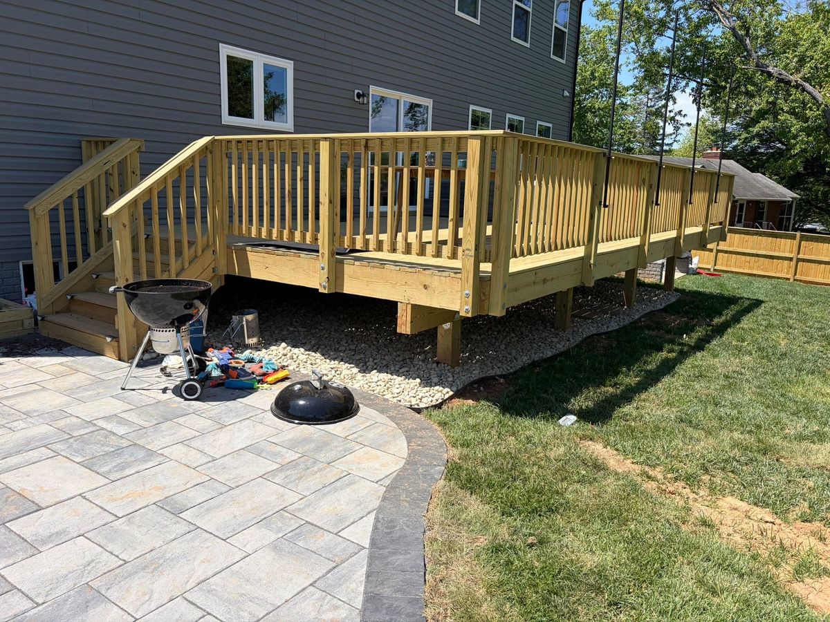 New wood deck and paver patio behind a house