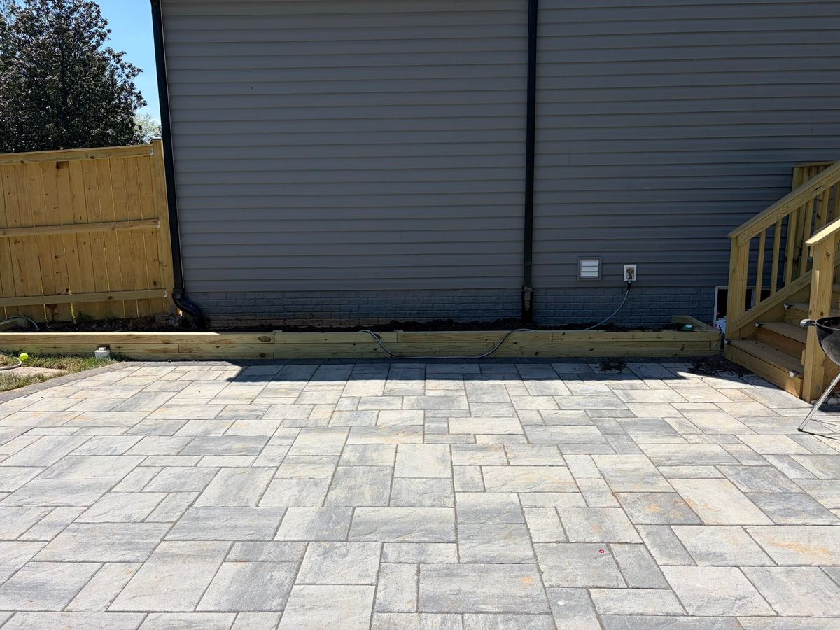 Large concrete paver patio finished against the back of a house