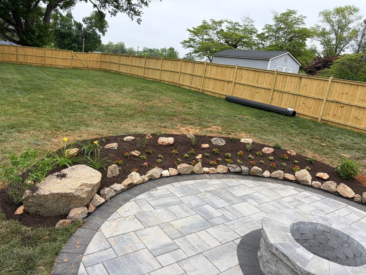 Round paver patio with a fire pit beside a new fence