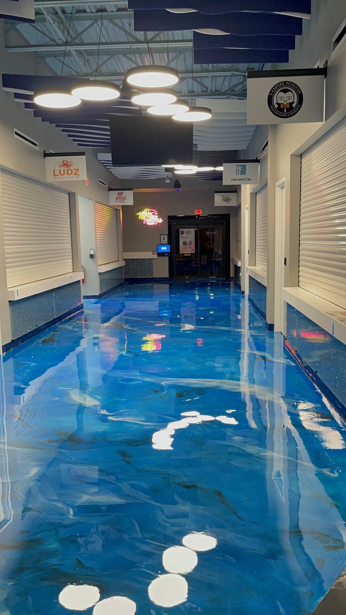 Blue metallic epoxy floor running down a commercial entertainment hallway