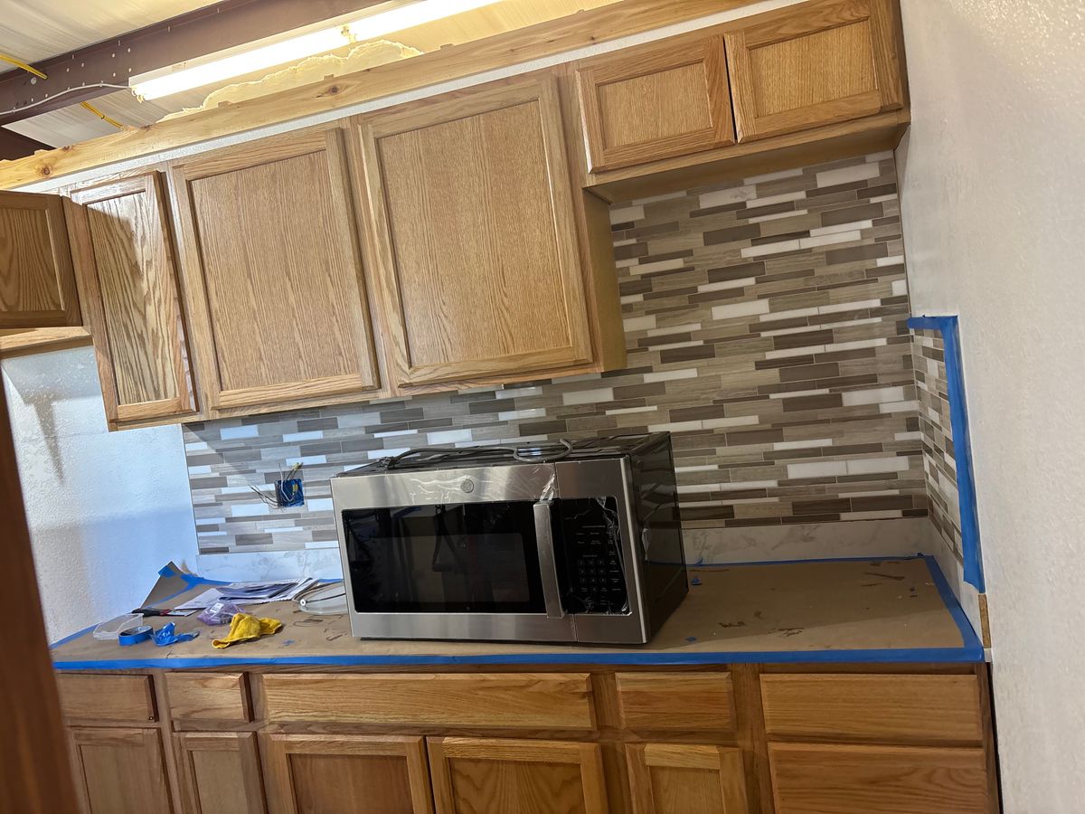 Tile backsplash going in with blue tape on the counter