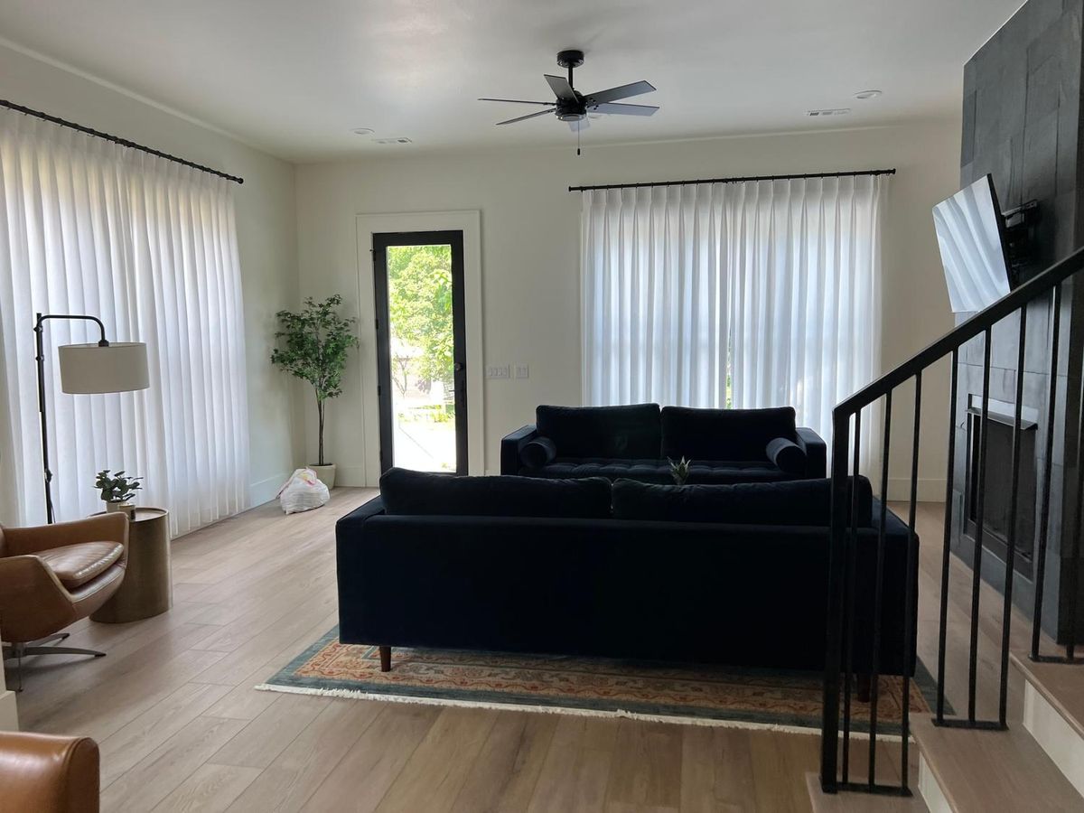 Living room with a black sofa and clean floors after a house cleaning