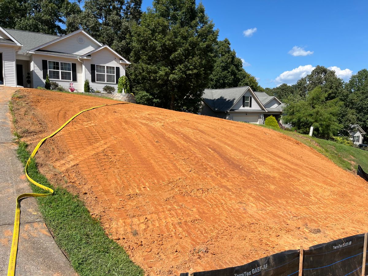 Black silt fence along the bottom of a graded front slope before seeding