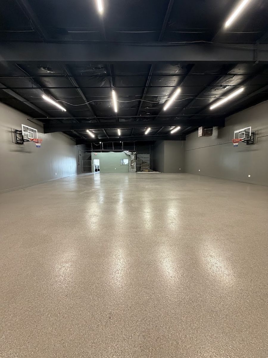 Glossy epoxy garage floor with speckled flakes reflecting rows of ceiling lights