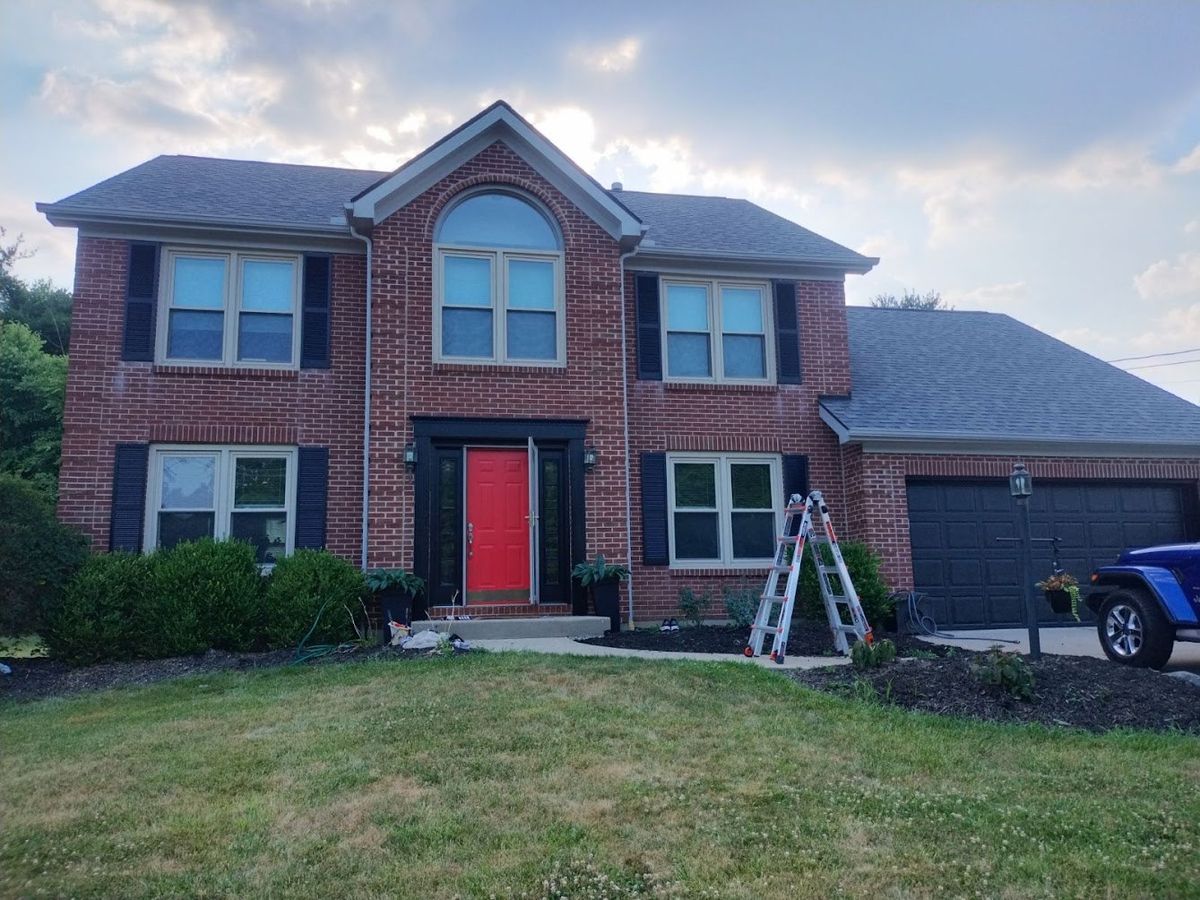 Two-story brick home with black shutters and a red front door after exterior painting in the Cincinnati area