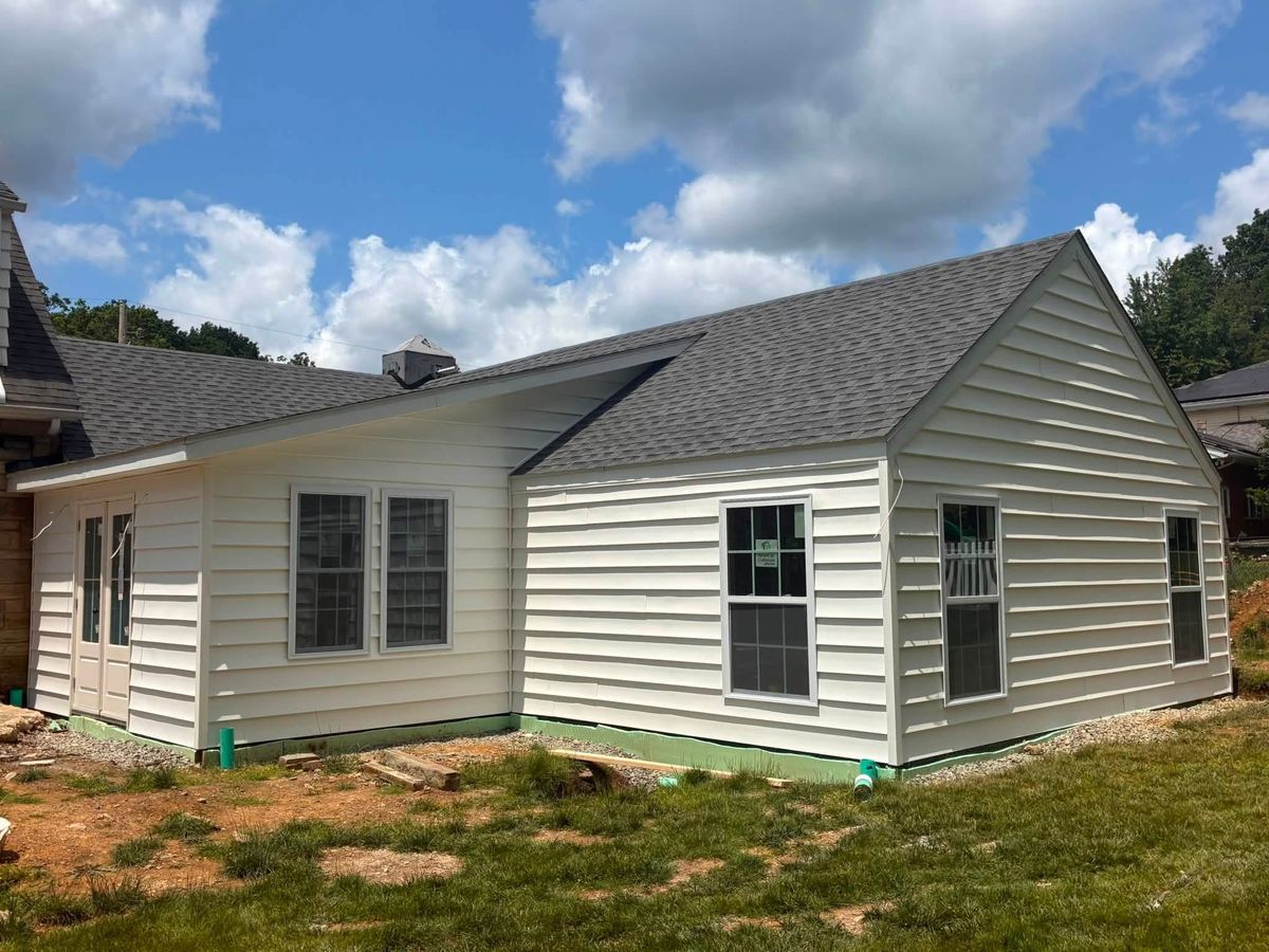 Home addition with new white vinyl siding, new windows and a gray shingle roof