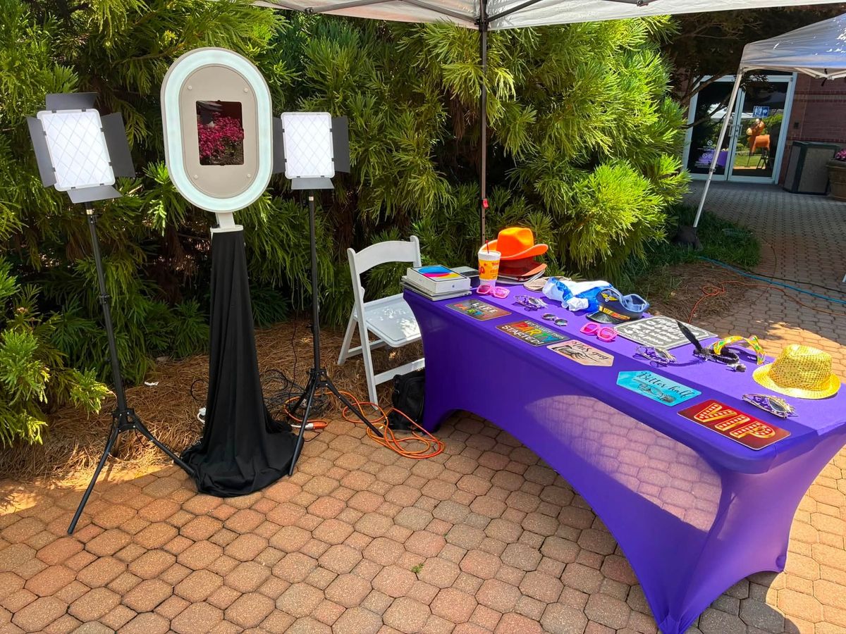 Selfie photo booth with studio lights and a props table set up outdoors