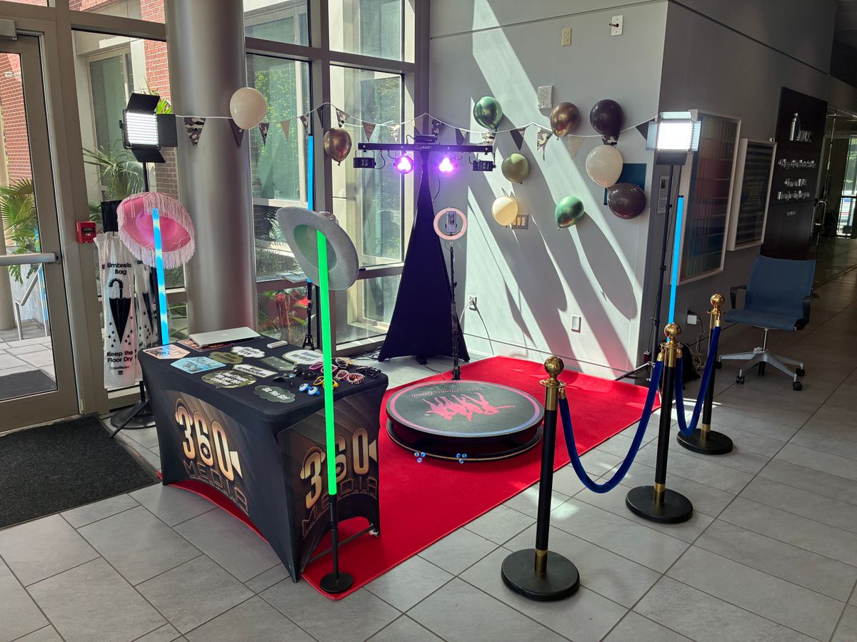 360 video booth platform with red carpet, stanchions, lighting, and a props table