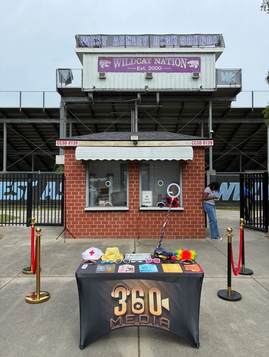 360 Media photo booth and props table set up outside a high school stadium