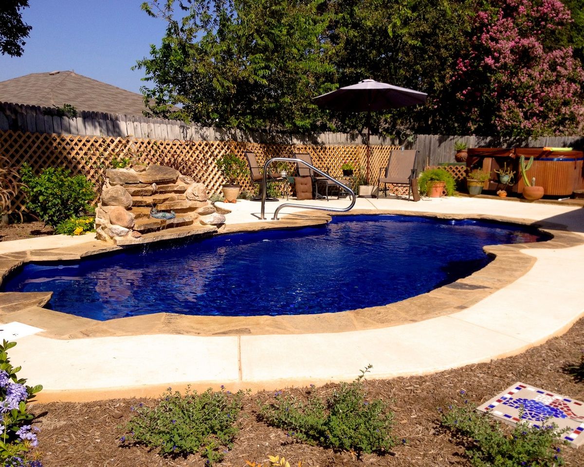 Blue pool with planting beds and a patio beside it