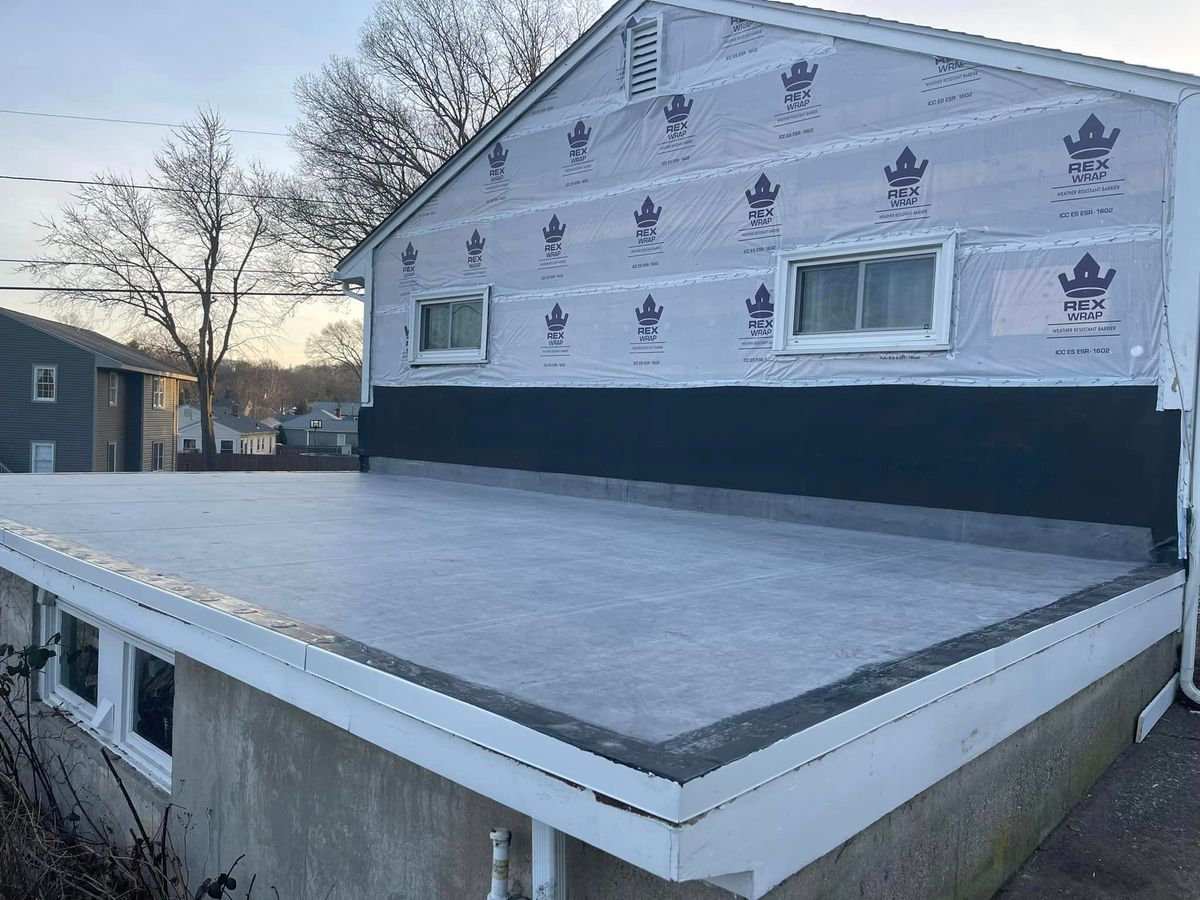 Newly installed rubber flat roof and house wrap on a home exterior tear off