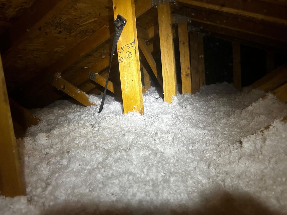 Finished Phoenix attic with deep, even blown-in insulation under gable vent light
