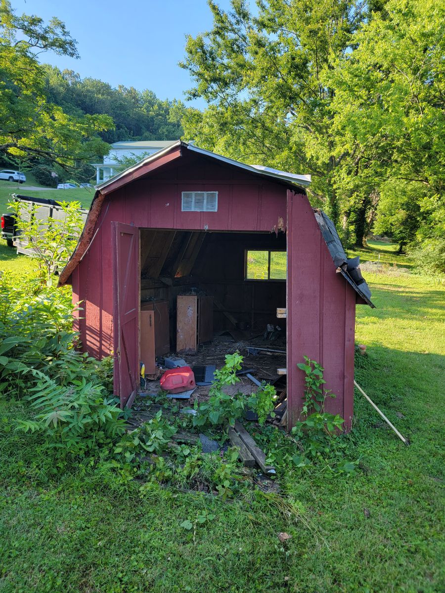 Old red barn style shed in a backyard before removal