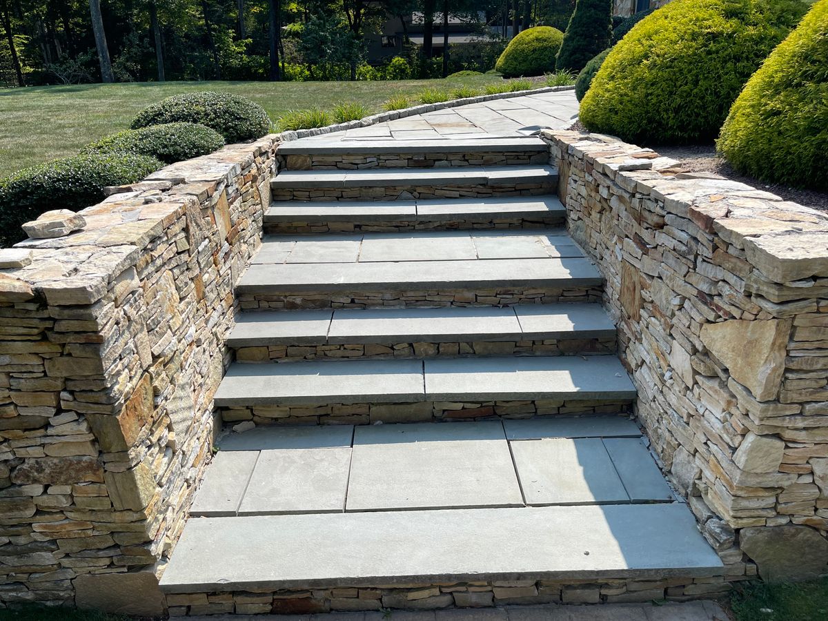 Wide bluestone steps and walkway framed by natural stone retaining walls