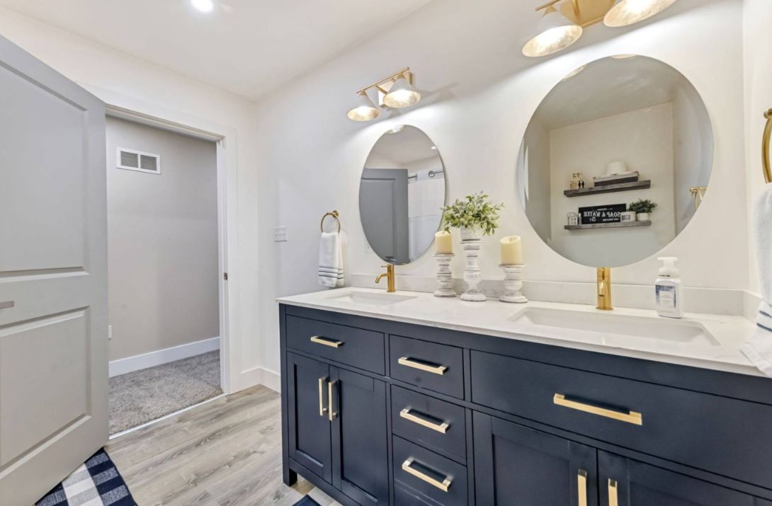 Bathroom with a navy double vanity, two round mirrors and brass fixtures