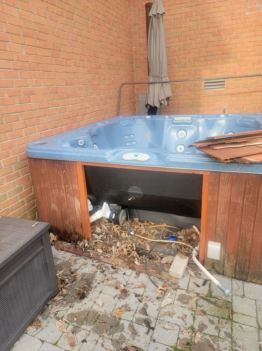 Old hot tub sitting on a brick-walled patio before removal