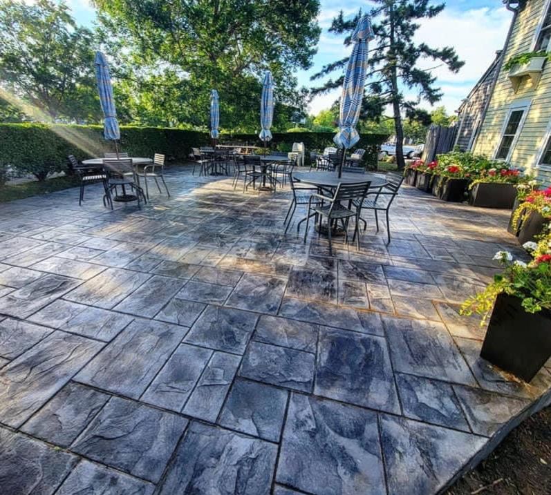 Large stamped concrete dining patio with cafe tables and umbrellas at a waterfront restaurant