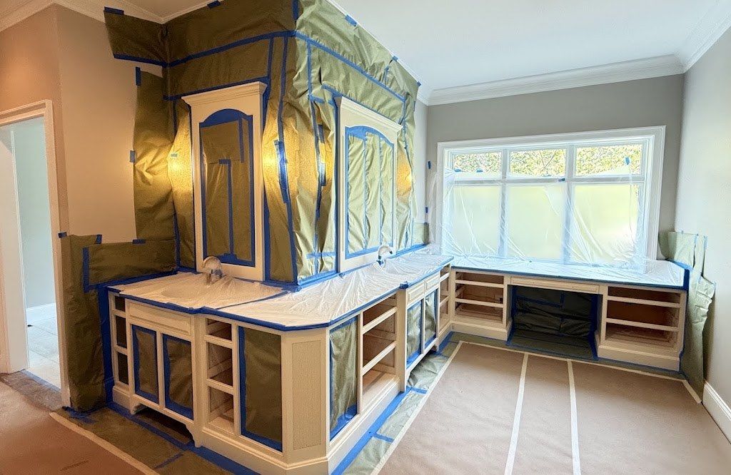 Kitchen cabinets and built-ins masked with tape and plastic, ready to be sprayed