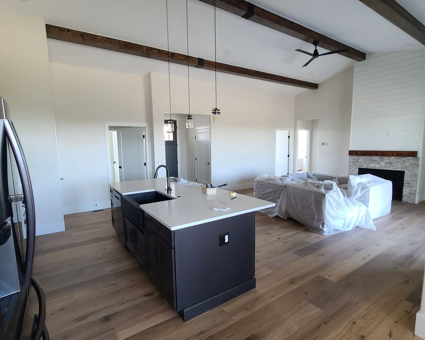 Renovated kitchen with a black island, pendant lights and white oak flooring