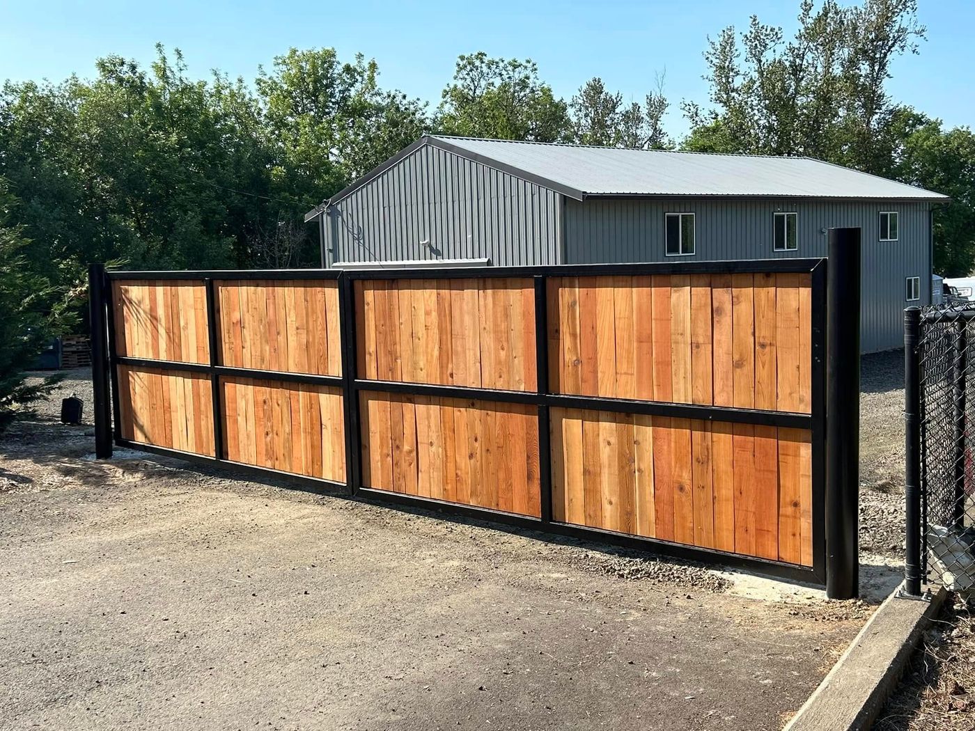 Cedar-slat sliding driveway gate on a black steel frame