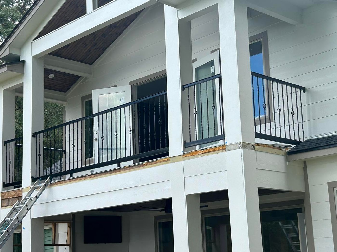 Black iron balcony railing on a white two-story house