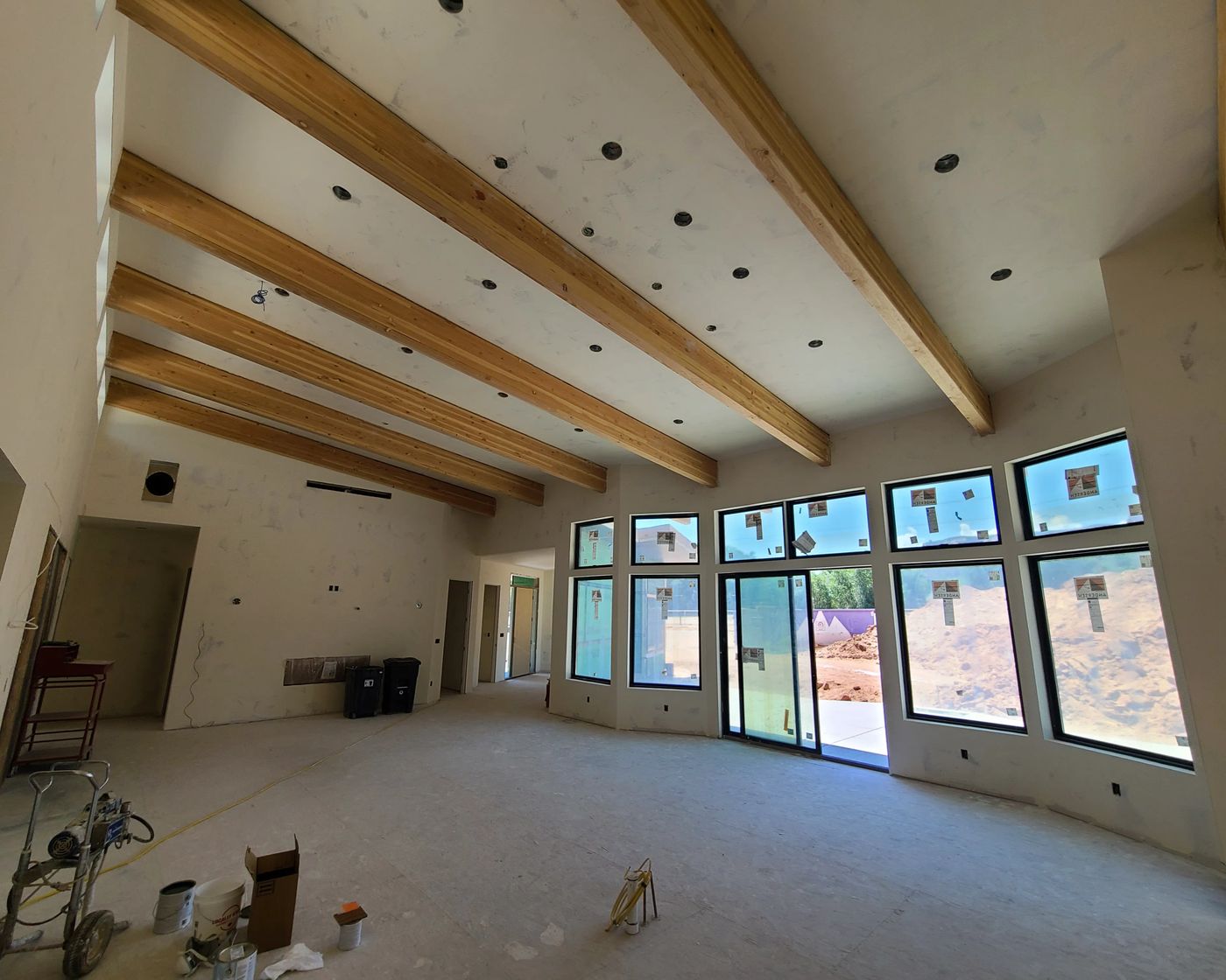 Great room with exposed beams and a wall of windows mid-renovation