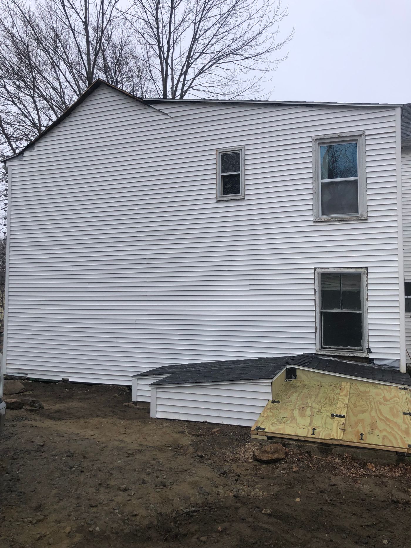 Finished bulkhead entry with a low roof on the side of a white house
