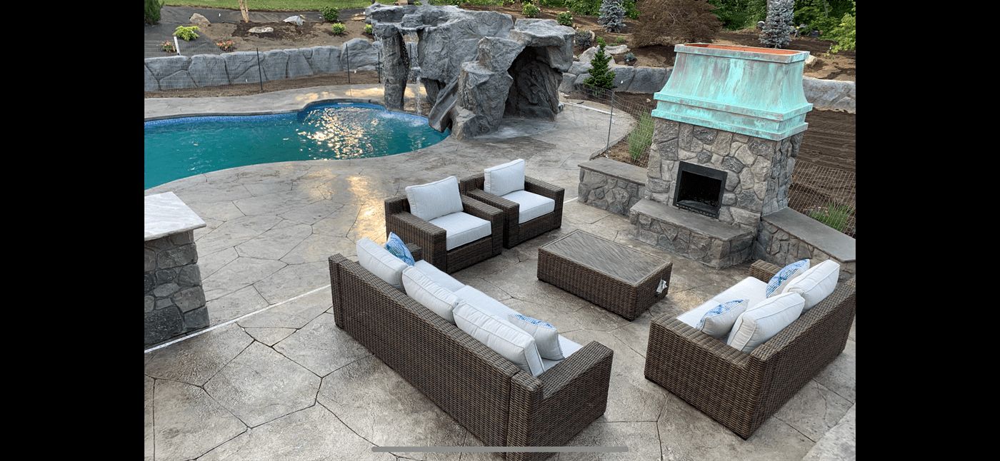 Pool patio with a rock waterfall, outdoor fireplace and seating