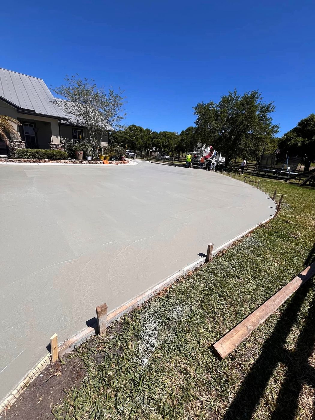 Wide curved concrete driveway forming beside a lawn