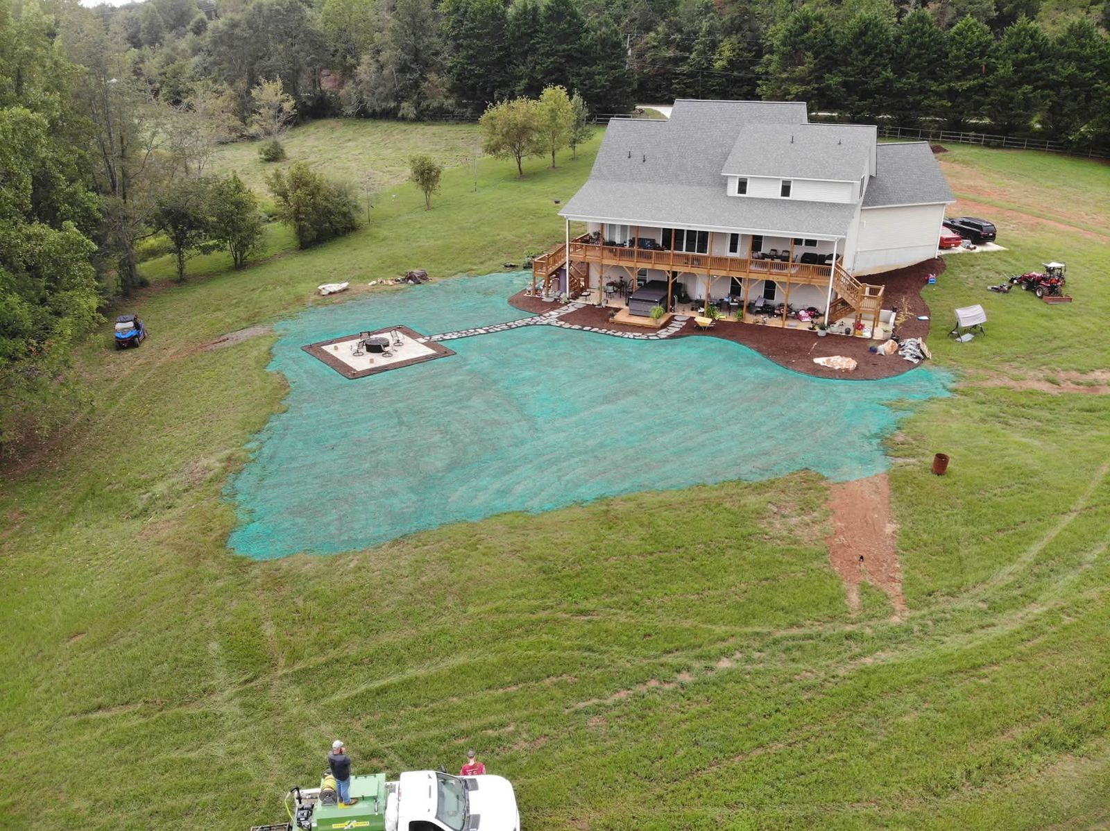 Drone view of a farmhouse with a freshly sprayed hydroseed lawn and the 4 G's truck below