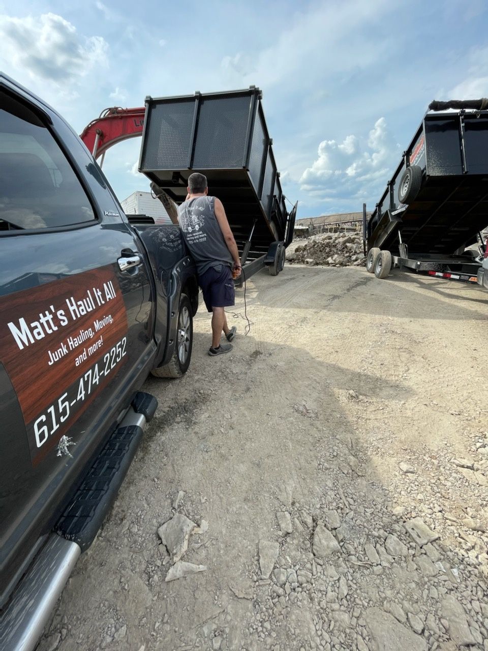 Matt's Haul it All pickup with a worker walking beside roll-off dumpsters at a job site