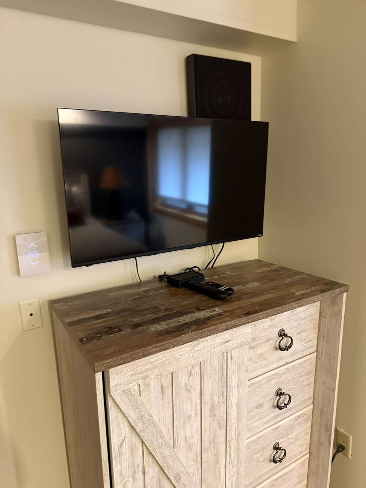 Flat screen television mounted on the wall above a dresser in a Vermont home