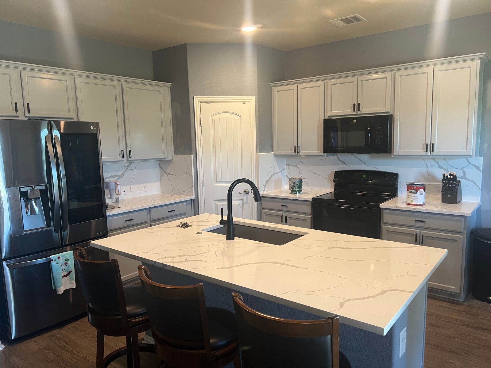 Finished kitchen with white cabinets, a quartz island and black hardware