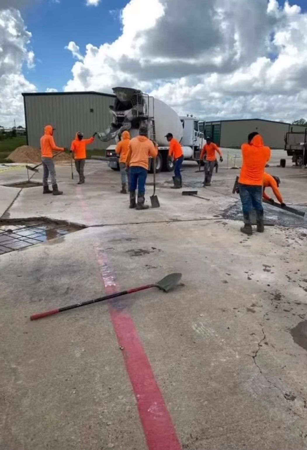 Rytren Concrete crew in orange hi-vis shirts working on a section of a concrete lot with a ready-mix truck behind them