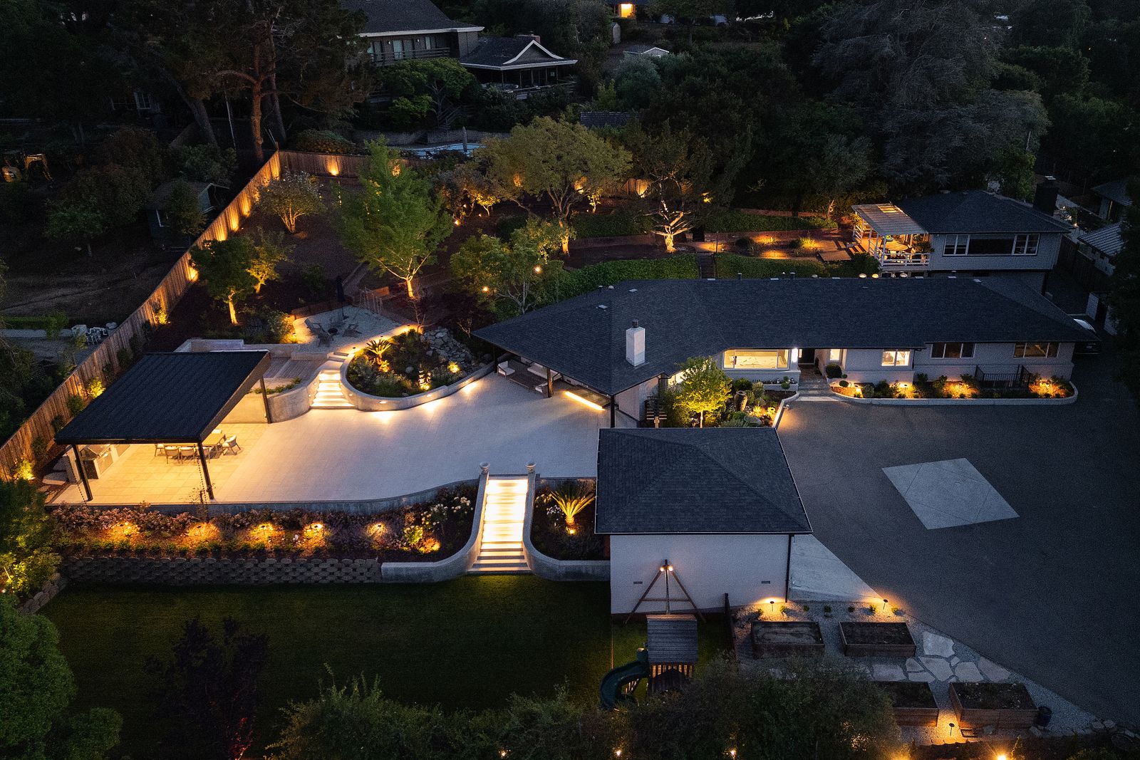 Night aerial of the terraced garden, the curved retaining walls and steps lit along their length