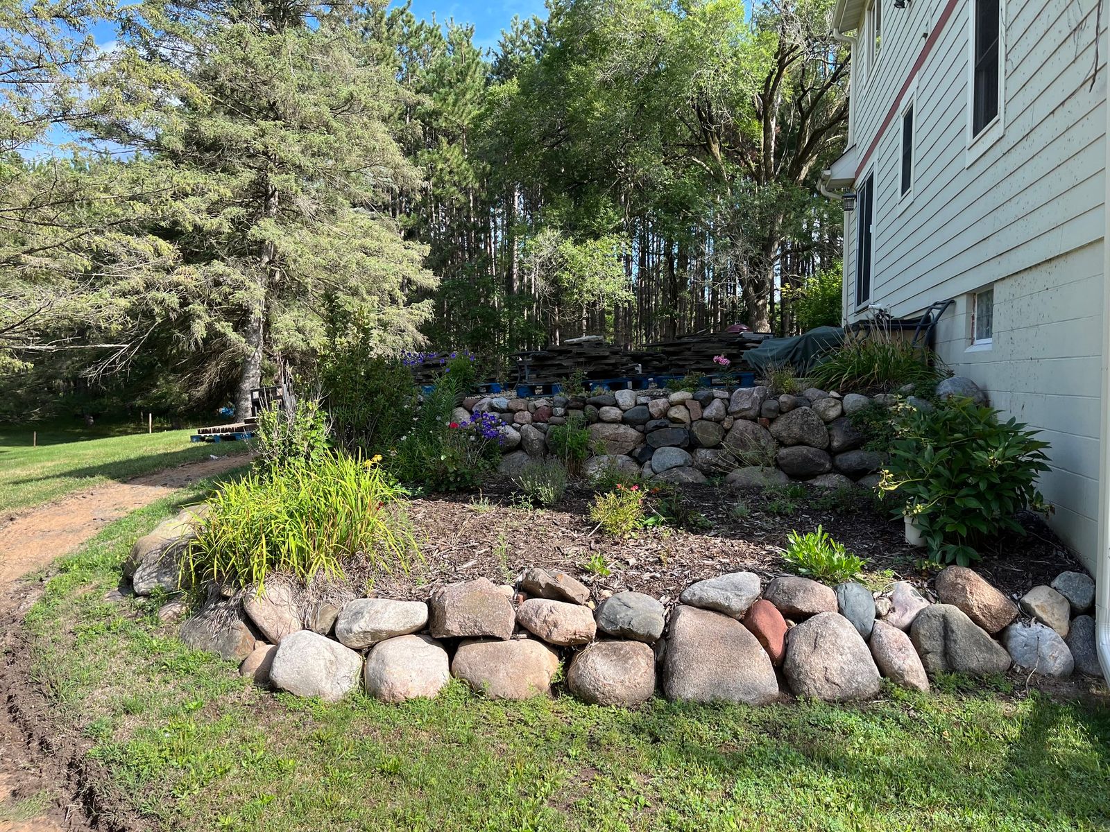 Boulder retaining wall with ornamental grasses and fresh mulch on a slope