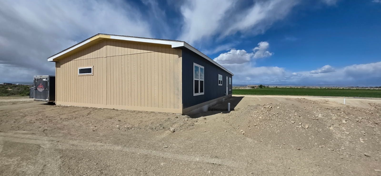 Tan and charcoal modular home exterior under a big Western Slope sky