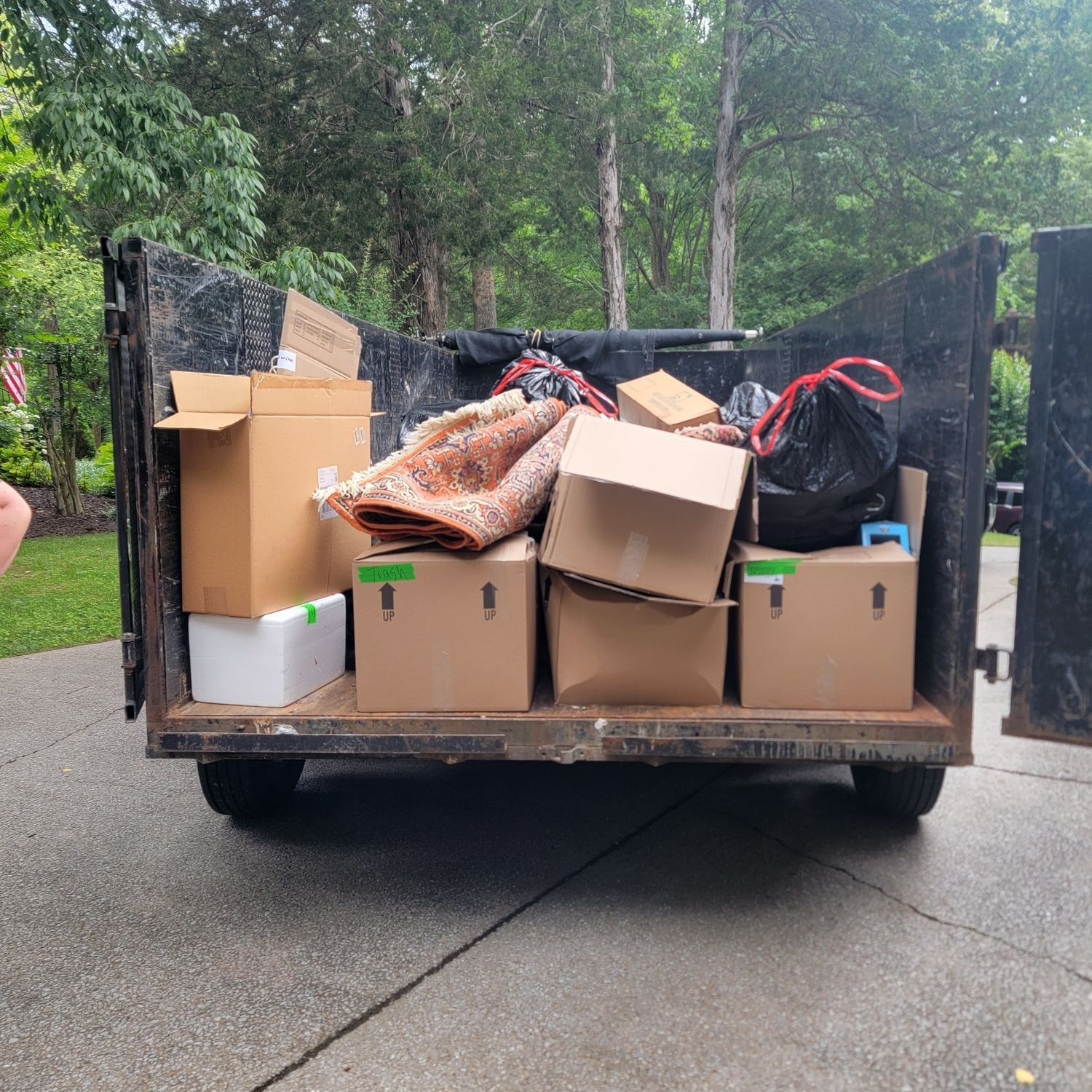 Trailer packed with boxes and bags in a driveway, loaded for a donation run