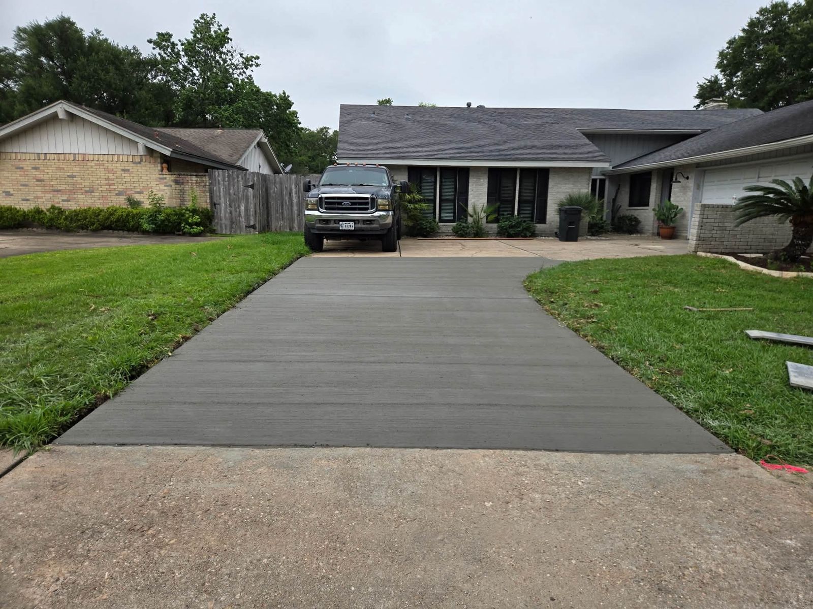 Freshly finished concrete driveway in front of a ranch-style house