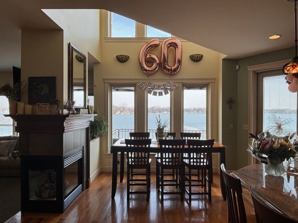 Lake-house dining table by bright windows over clean wood floors, ready for guests